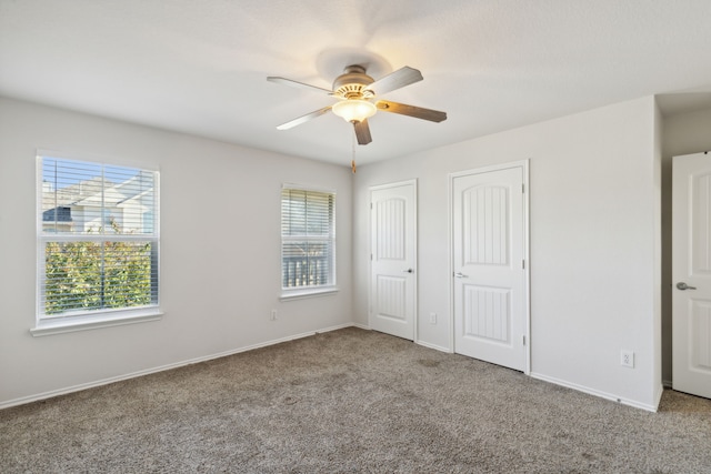 unfurnished bedroom with carpet flooring, ceiling fan, and multiple closets