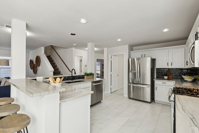 kitchen featuring light stone counters, white cabinetry, sink, and appliances with stainless steel finishes