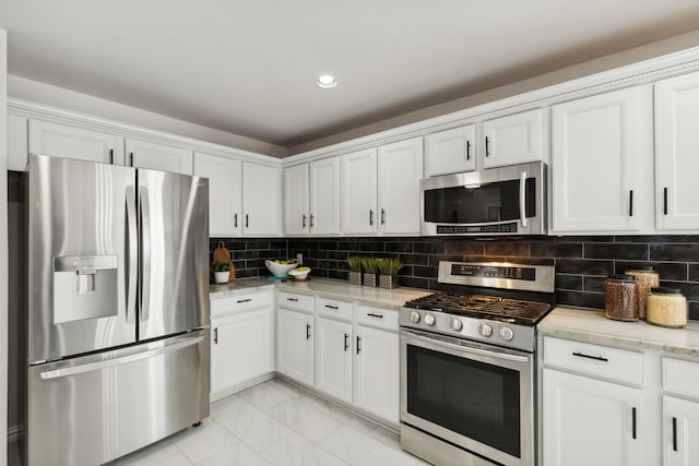 kitchen with tasteful backsplash, light stone countertops, white cabinets, and appliances with stainless steel finishes