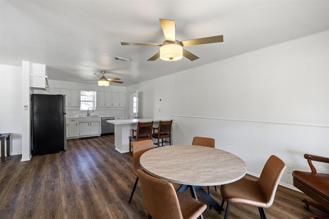 dining area with dark hardwood / wood-style flooring, ceiling fan, sink, and wood walls