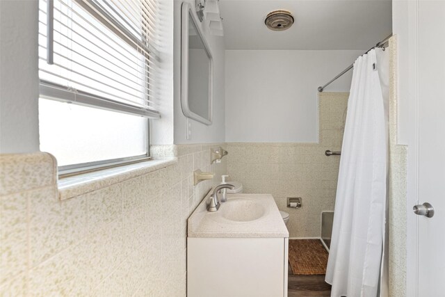 bathroom featuring walk in shower, wood-type flooring, vanity, and tile walls