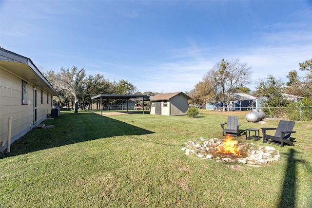 view of yard featuring central AC unit, a carport, an outdoor fire pit, and a shed