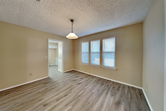 spare room featuring a textured ceiling and light hardwood / wood-style floors