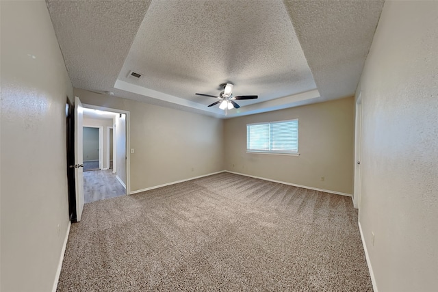 carpeted empty room featuring ceiling fan, a raised ceiling, and a textured ceiling