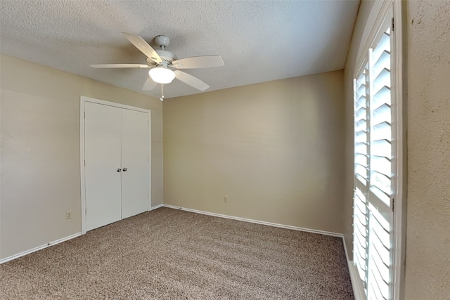 unfurnished bedroom featuring carpet, ceiling fan, a textured ceiling, and a closet