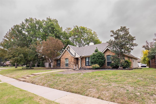 single story home with brick siding, a chimney, and a front yard