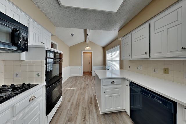 kitchen with kitchen peninsula, hanging light fixtures, black appliances, and a textured ceiling