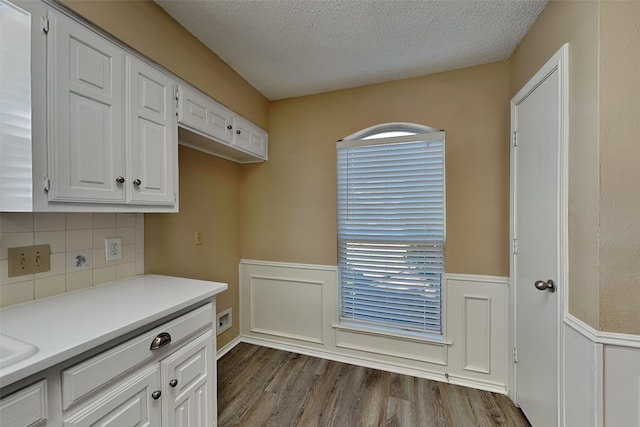 kitchen with white cabinets, wood-type flooring, a textured ceiling, and tasteful backsplash