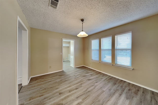 empty room with light wood-type flooring and a textured ceiling