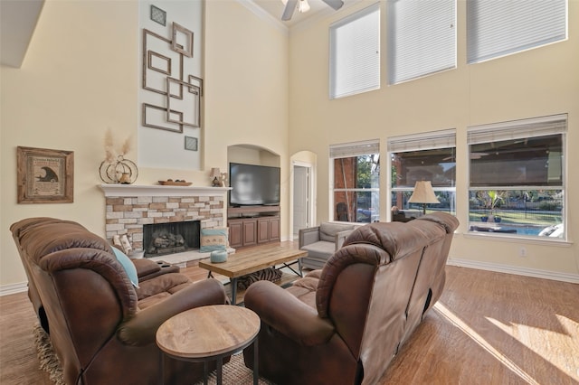 living room with a fireplace, a towering ceiling, ceiling fan, and crown molding