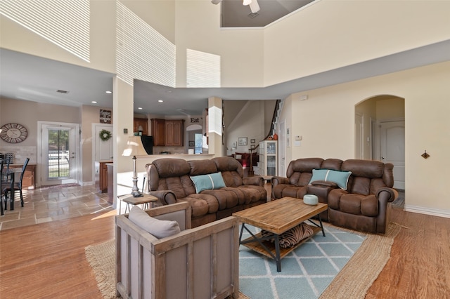 living room featuring ceiling fan, light hardwood / wood-style floors, and a high ceiling