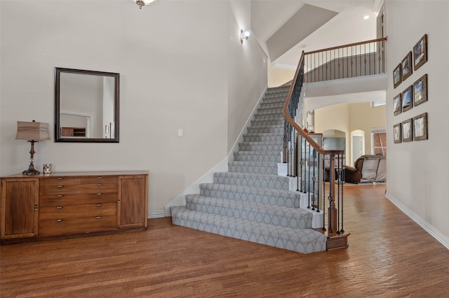 staircase with hardwood / wood-style floors and a high ceiling