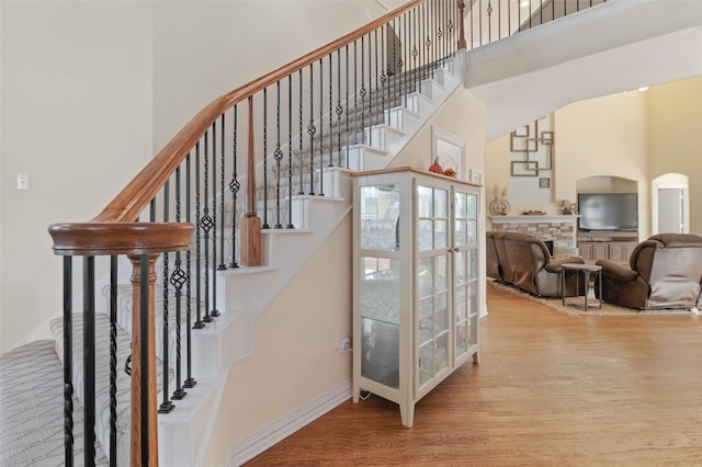 stairway with wood-type flooring and a high ceiling