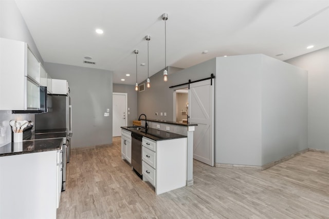 kitchen featuring pendant lighting, dishwasher, white cabinets, a barn door, and an island with sink