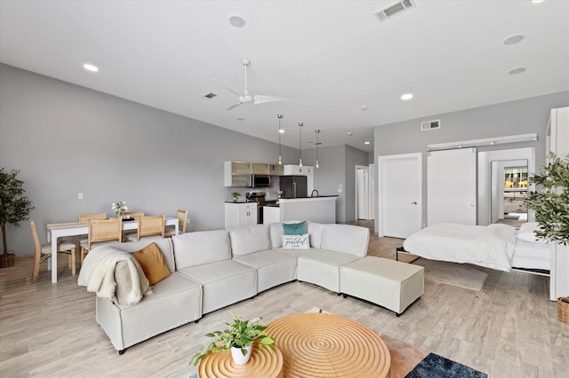 living room with ceiling fan, light hardwood / wood-style flooring, and lofted ceiling