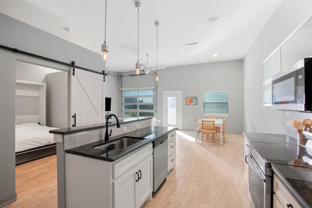 kitchen with white cabinetry, sink, a barn door, pendant lighting, and appliances with stainless steel finishes