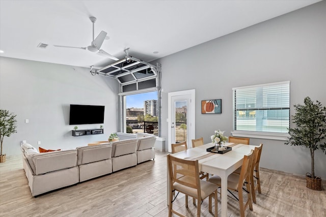 dining room with ceiling fan, vaulted ceiling, and light wood-type flooring