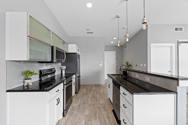 kitchen with kitchen peninsula, appliances with stainless steel finishes, sink, white cabinetry, and hanging light fixtures