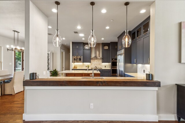 kitchen featuring kitchen peninsula, tasteful backsplash, stainless steel appliances, dark wood-type flooring, and sink