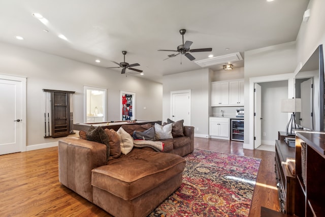 living room with bar area, ceiling fan, and wood-type flooring