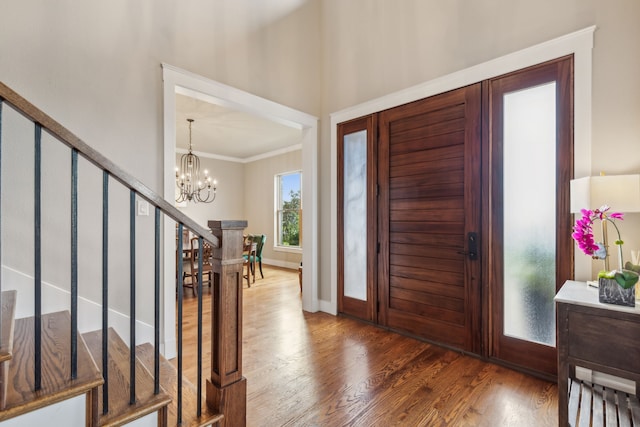 foyer with crown molding, dark hardwood / wood-style flooring, and a notable chandelier