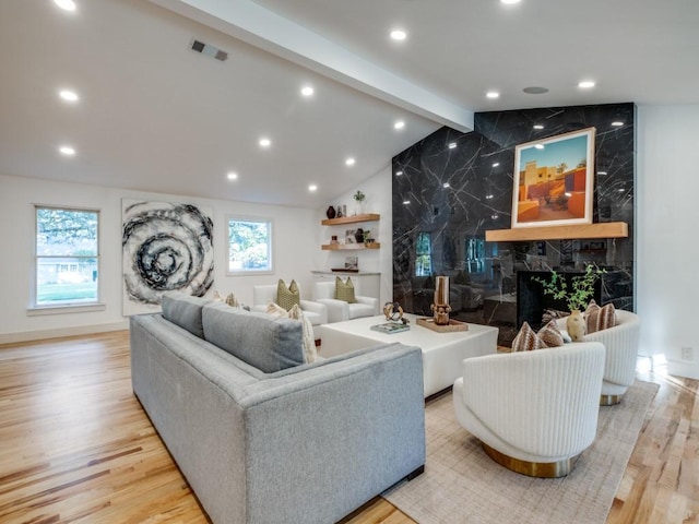 living room featuring a premium fireplace, vaulted ceiling with beams, and light hardwood / wood-style flooring