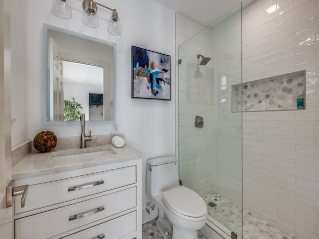 bathroom with a tile shower, vanity, and toilet