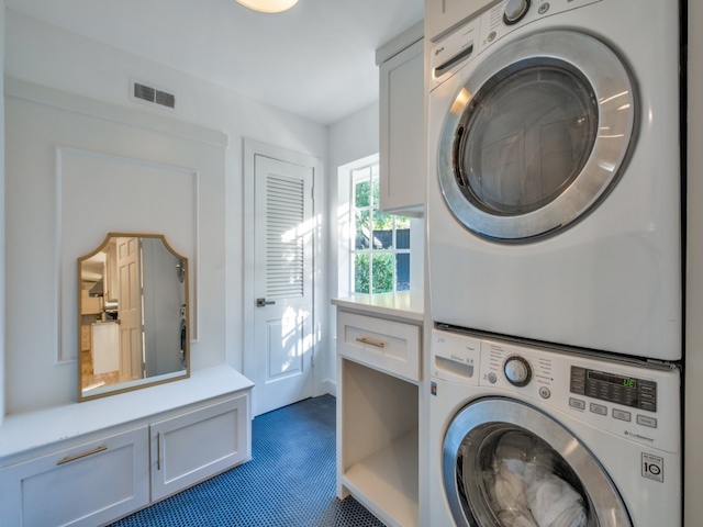 laundry room with stacked washer / dryer and cabinets