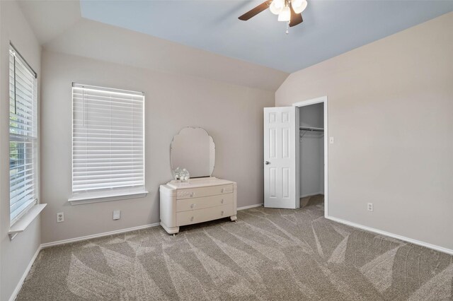 unfurnished bedroom featuring ceiling fan, a closet, light carpet, and lofted ceiling