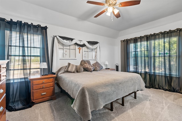 bedroom featuring multiple windows, vaulted ceiling, ceiling fan, and carpet