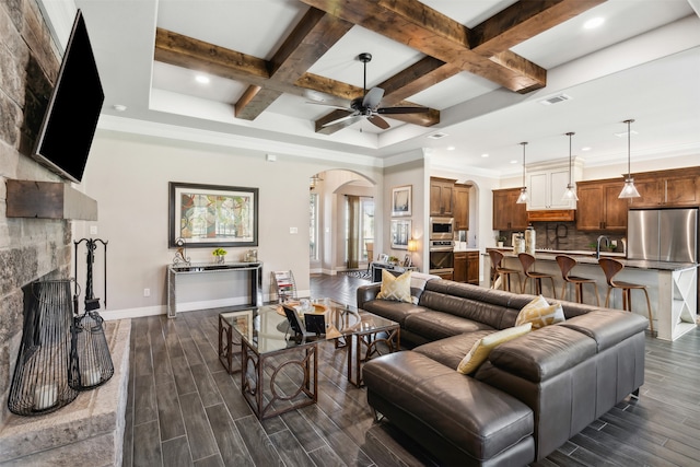 living room featuring a fireplace, beamed ceiling, dark wood-type flooring, and coffered ceiling