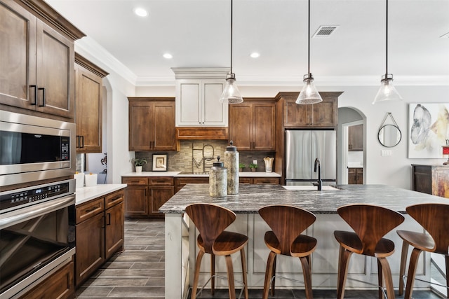 kitchen featuring pendant lighting, a center island, crown molding, and appliances with stainless steel finishes