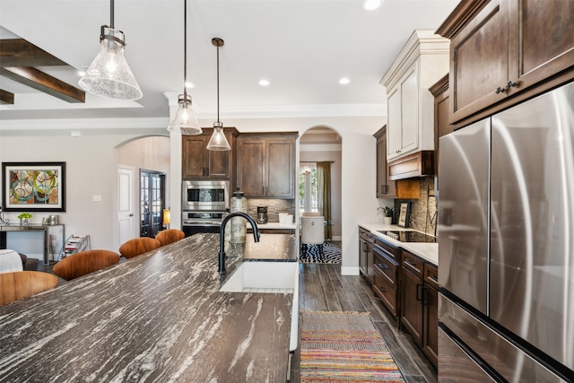 kitchen with decorative backsplash, sink, built in appliances, decorative light fixtures, and dark hardwood / wood-style floors