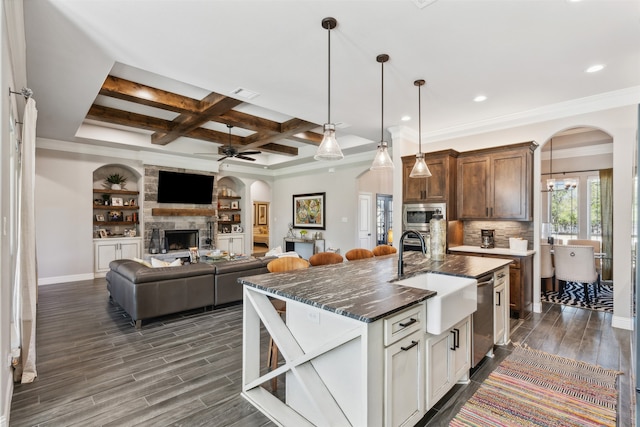 kitchen with sink, dark wood-type flooring, coffered ceiling, a fireplace, and a center island with sink