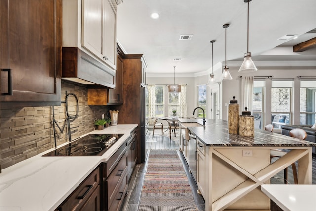 kitchen featuring decorative backsplash, dark stone counters, dark wood-type flooring, and a healthy amount of sunlight