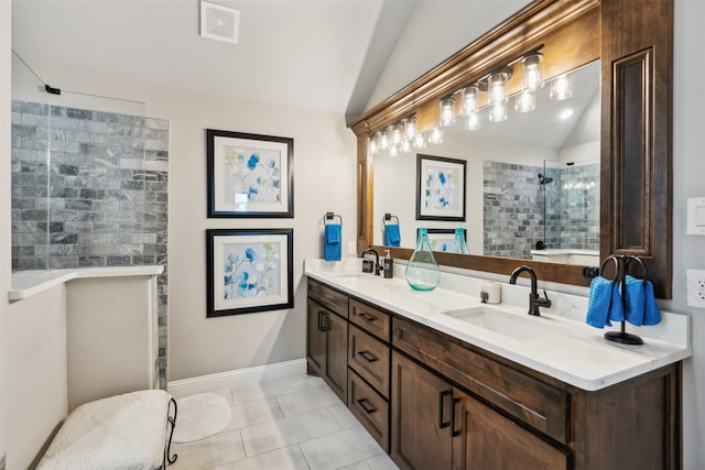 bathroom with a tile shower, tile patterned floors, vanity, and lofted ceiling