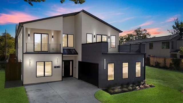 contemporary house featuring a yard, a balcony, and a garage