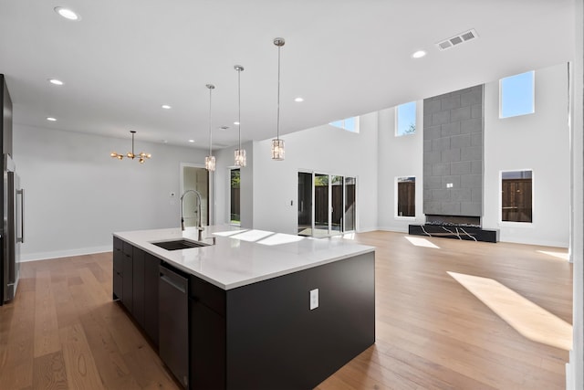 kitchen with pendant lighting, stainless steel dishwasher, a spacious island, and sink