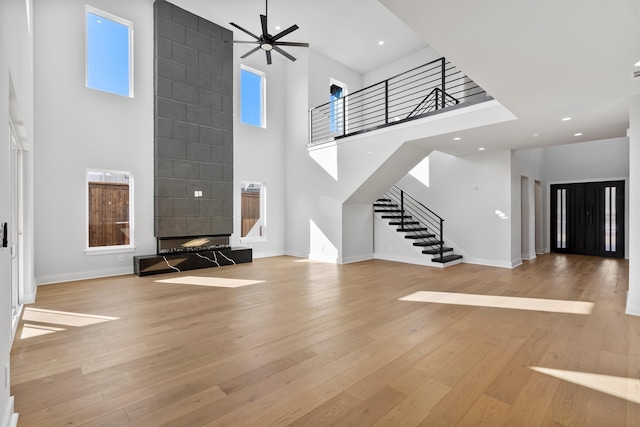 unfurnished living room featuring ceiling fan, light hardwood / wood-style floors, and a high ceiling