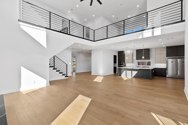 unfurnished living room featuring a high ceiling and light hardwood / wood-style flooring