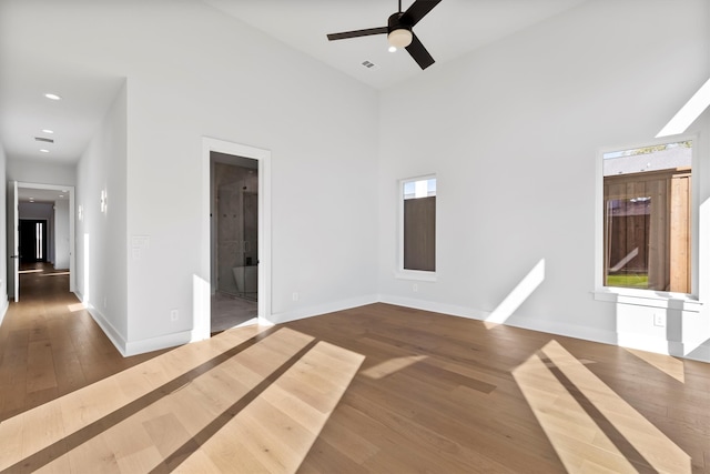 spare room featuring hardwood / wood-style flooring, ceiling fan, and a towering ceiling