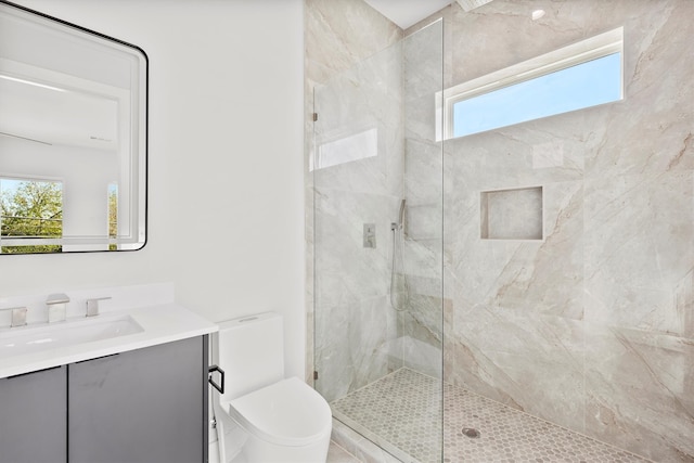 bathroom featuring tiled shower, plenty of natural light, vanity, and toilet