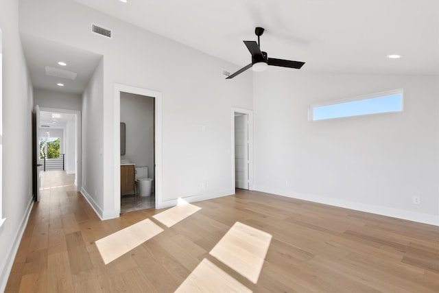 unfurnished bedroom featuring lofted ceiling, light wood-type flooring, multiple windows, and ensuite bath