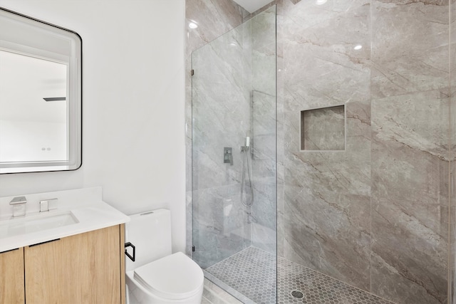 bathroom featuring tiled shower, vanity, and toilet