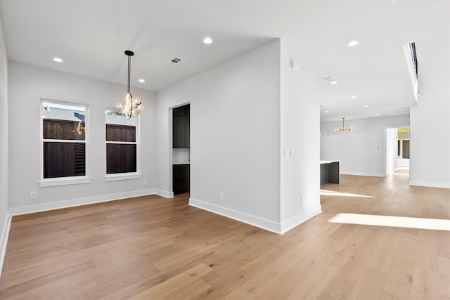 unfurnished room with light hardwood / wood-style floors and an inviting chandelier