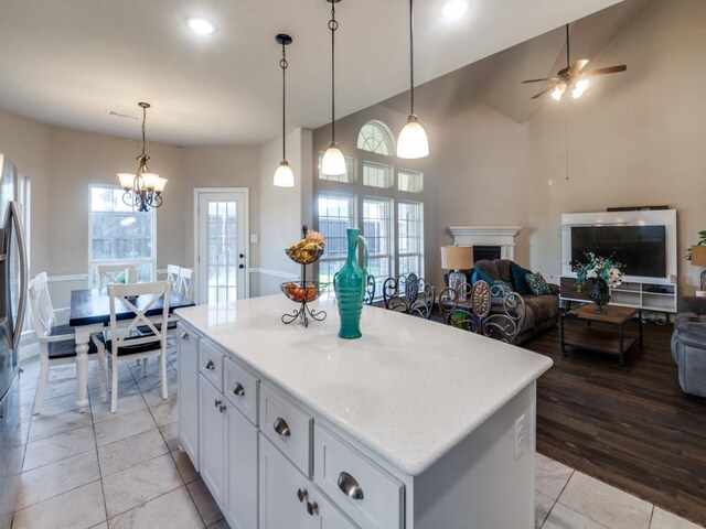 kitchen with a wealth of natural light, a center island, white cabinets, and decorative light fixtures