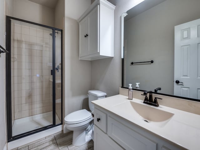 bathroom featuring vanity, toilet, and a shower with shower door