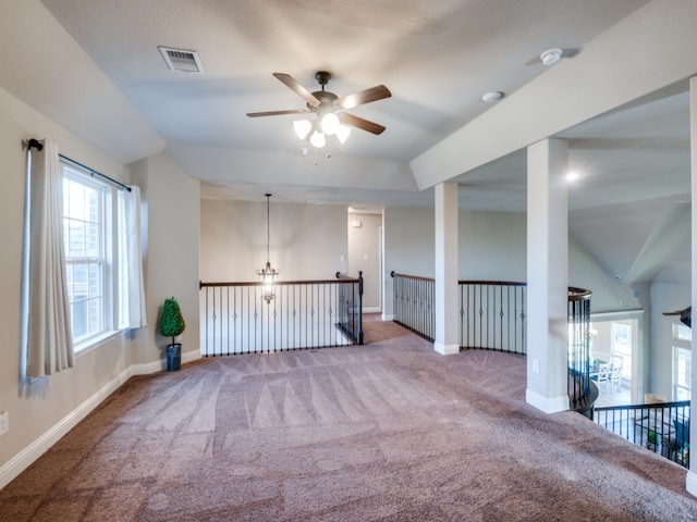 carpeted empty room featuring lofted ceiling and ceiling fan with notable chandelier