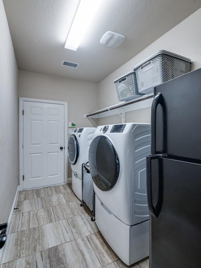 laundry area featuring a textured ceiling and washing machine and clothes dryer