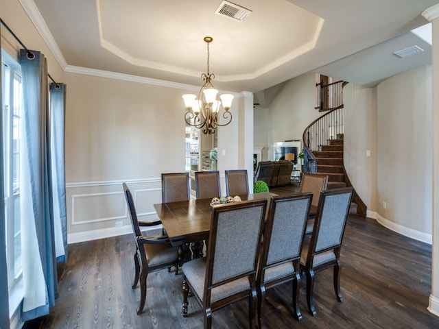 dining room with a tray ceiling, ornamental molding, dark hardwood / wood-style floors, and an inviting chandelier